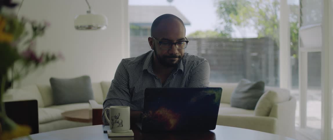 A man works on his laptop in his dining room
