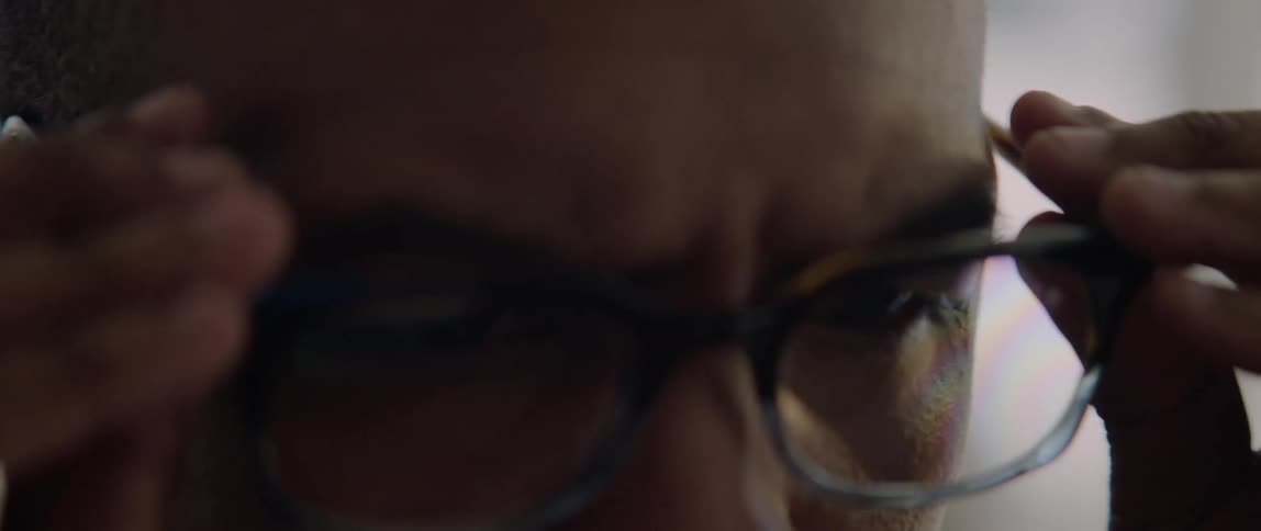 Close up of a man putting on glasses