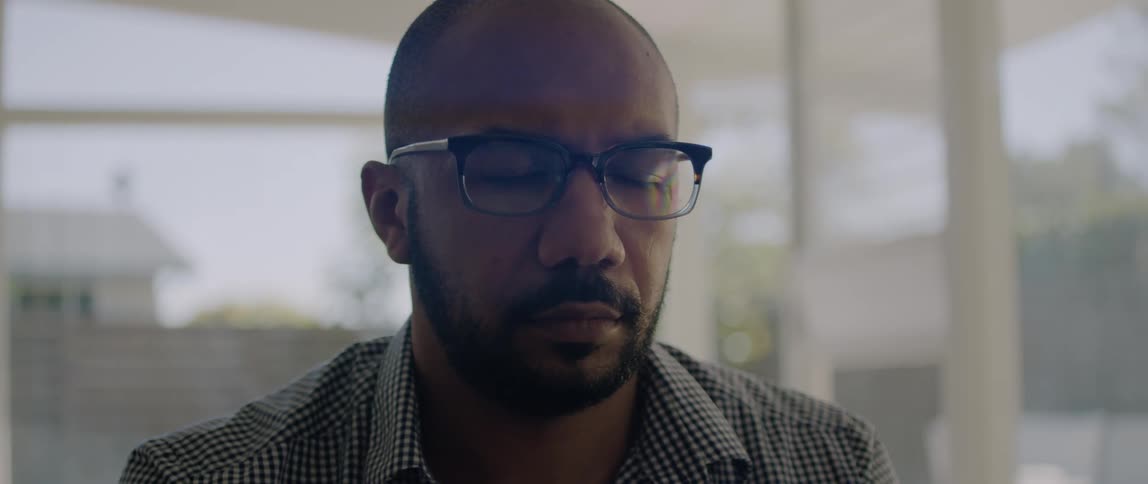 Young man wearing glasses sits in the office with his eyes closed thinking