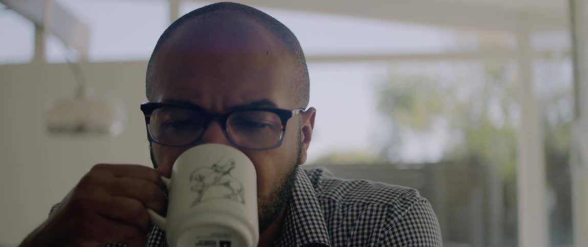 A man is sitting in his house drinking a cup of coffee