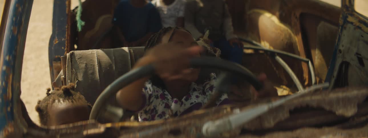 Kids play in interior of ruin vehicle pretending to take a trip