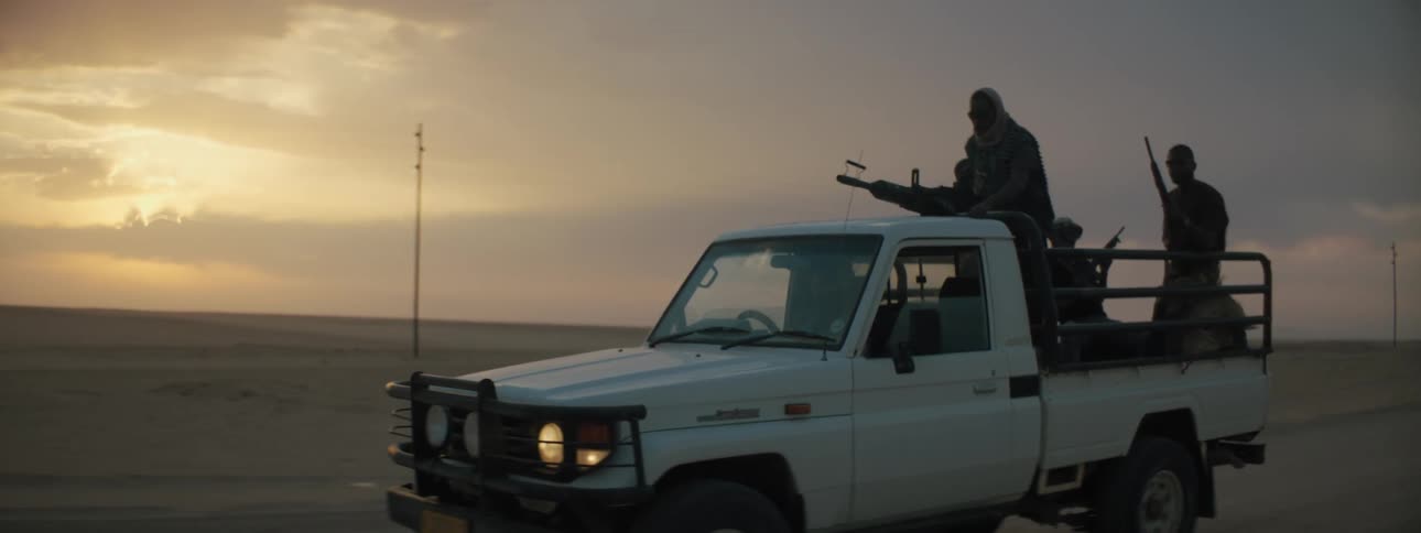 Group of militia on truck driving through the desert