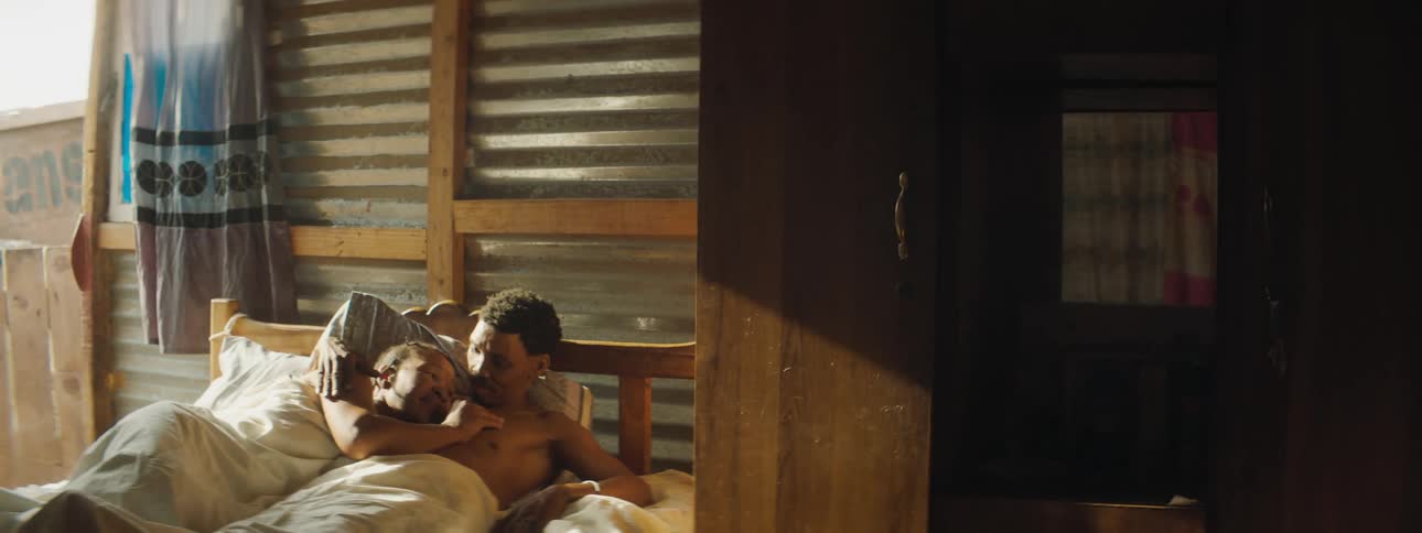 A woman rubs a mans chest as they lie in bed together
