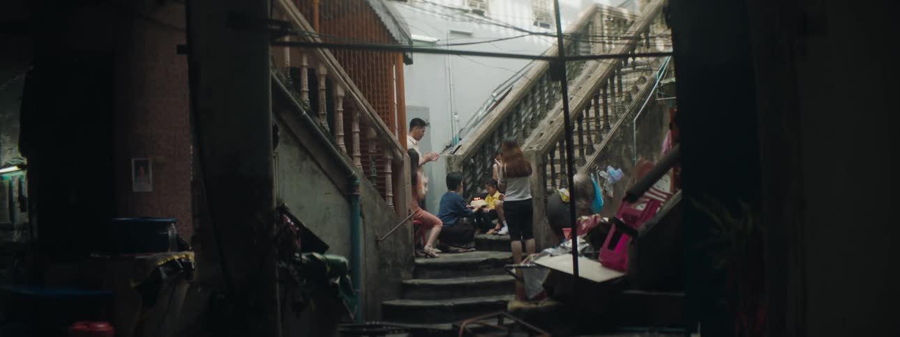 People standing in a staircase while clapping and bringing a birthday cake to a girl