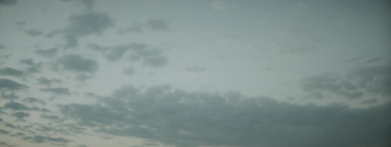 Woman sitting on sand dune is silhouetted against the sky in the desert at dusk