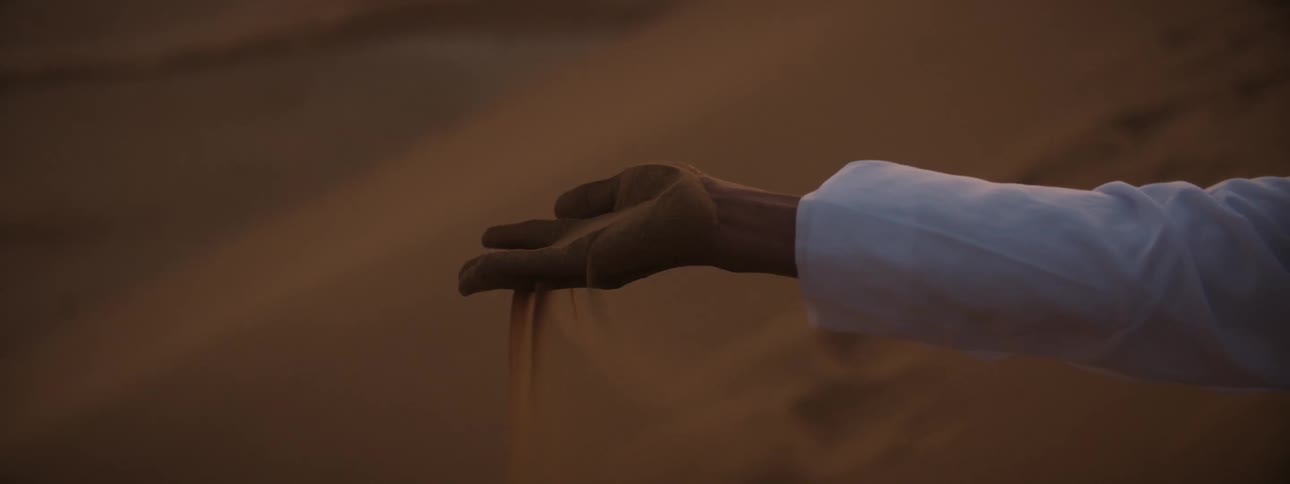 A person with a handful of sand in a desert