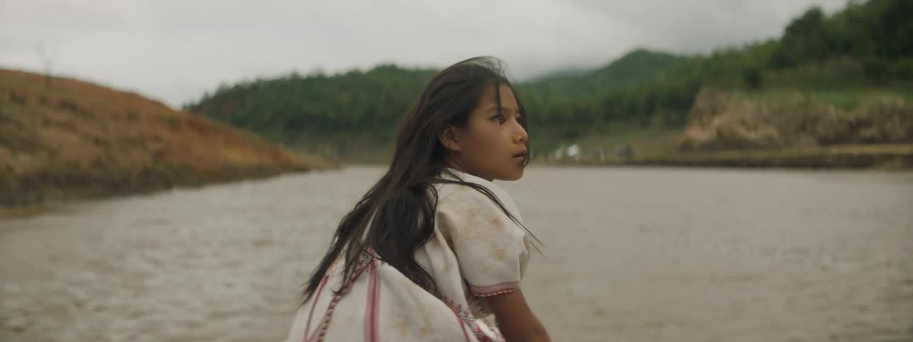 A young girl sits on a boat and rides through a lake