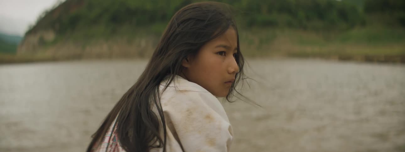 A girl rides a boat in the water towards land