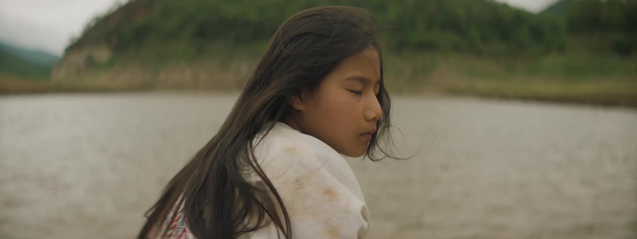 Young woman near a lake as the breeze blows her hair
