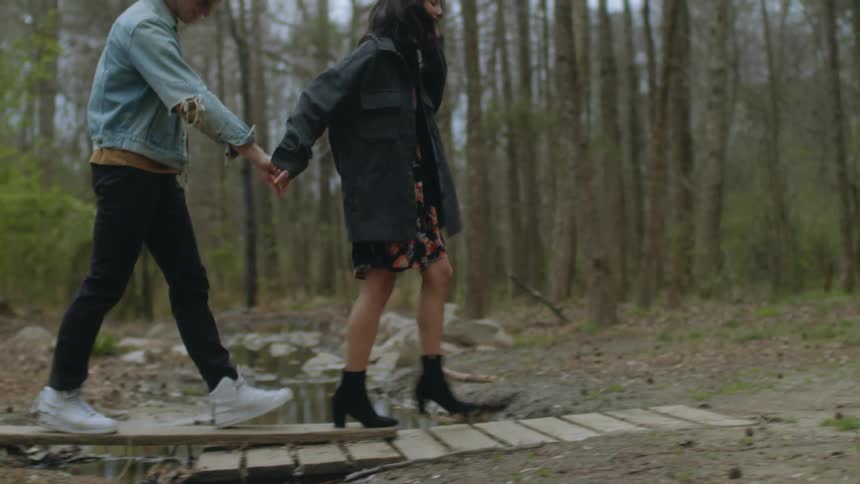 Teenagers hold hands while walking in the woods