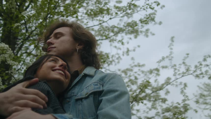 Young couple smile while hugging lovingly in front of a tree