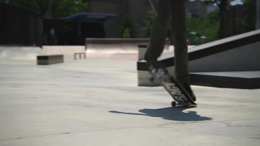 Young teenager with curly hair rides a skateboard on a skate park at daytime