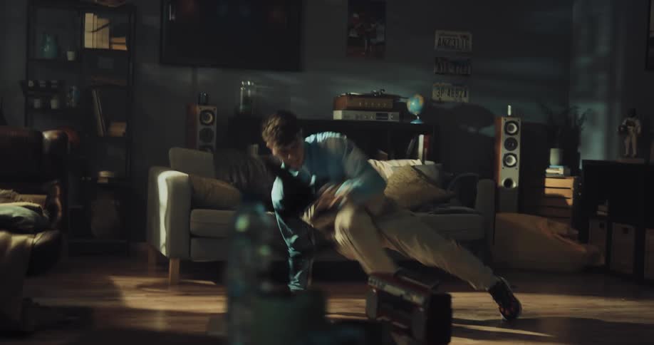 A teenage boy break dances in his living room
