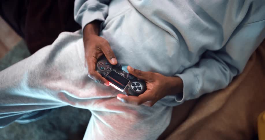 Man sitting on the couch at home playing with a video game control