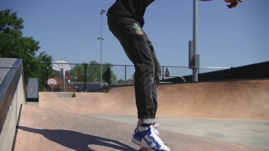 Male skateboarder performs jump trick while rolling over skatepark