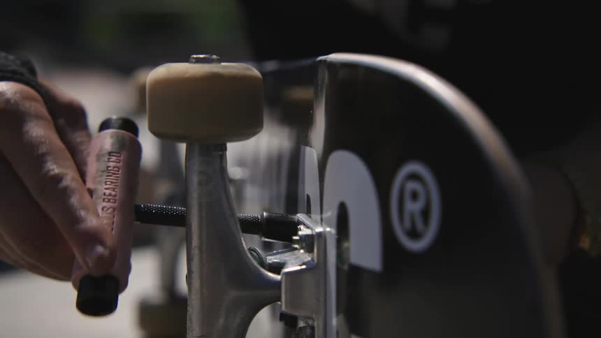 A man tightens the screws on his skateboard