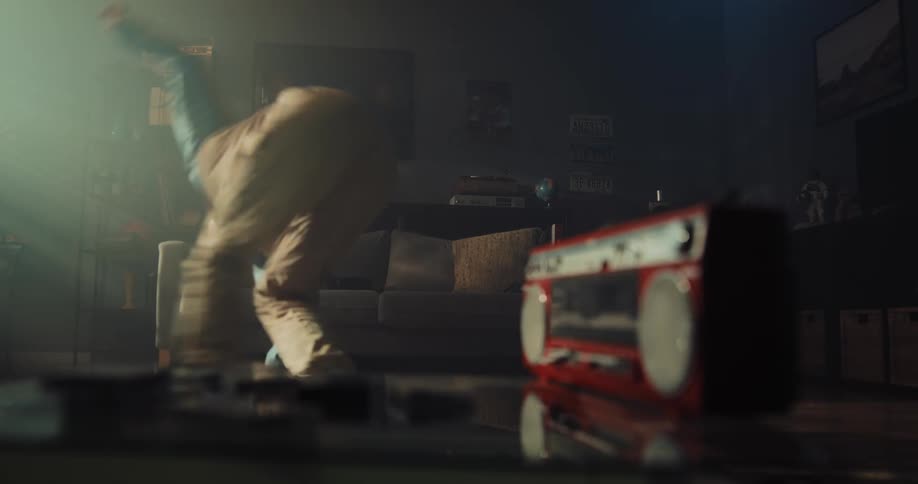 Man practices dancing in living room while listening to boombox