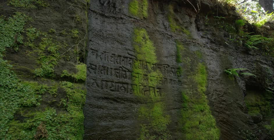 The wall of a cliff has writing etched in the side