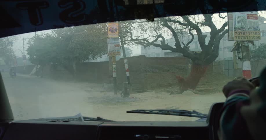 A vehicle drives past a rickshaw driver onto a street