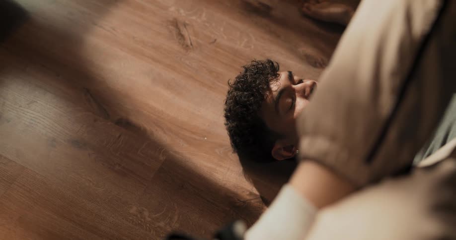 A man is laying on a wood floor stretching his legs
