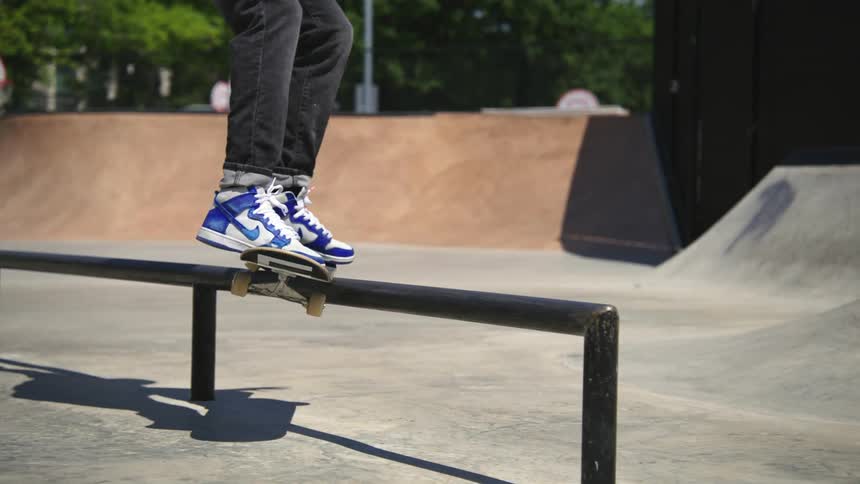 A man on a skateboard jumps up and rides a rail at the skate park