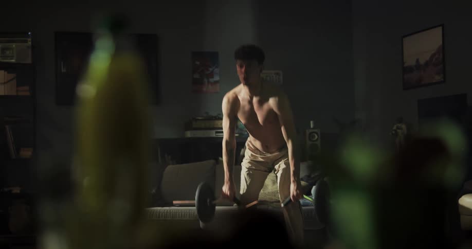 A teenage boy is standing in front of a couch working out with weights