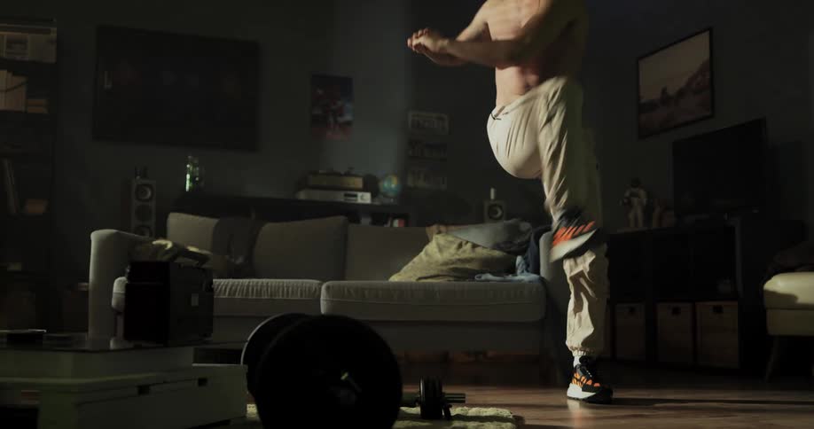 A man does leg lifts and side to side lunges in his living room