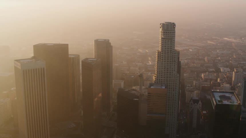 A group of skyscrapers loom over the much smaller surrounding buildings in a metropolis during the day