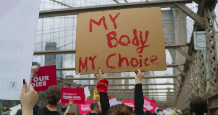Protesters march along bridge carrying signs