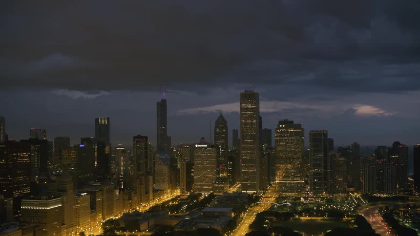 Tall building loom over the streets of a metropolis on a cloudy night