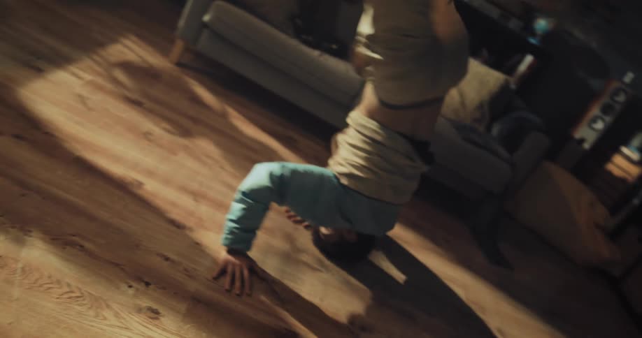 A teenage boy is breakdancing on a hardwood floor