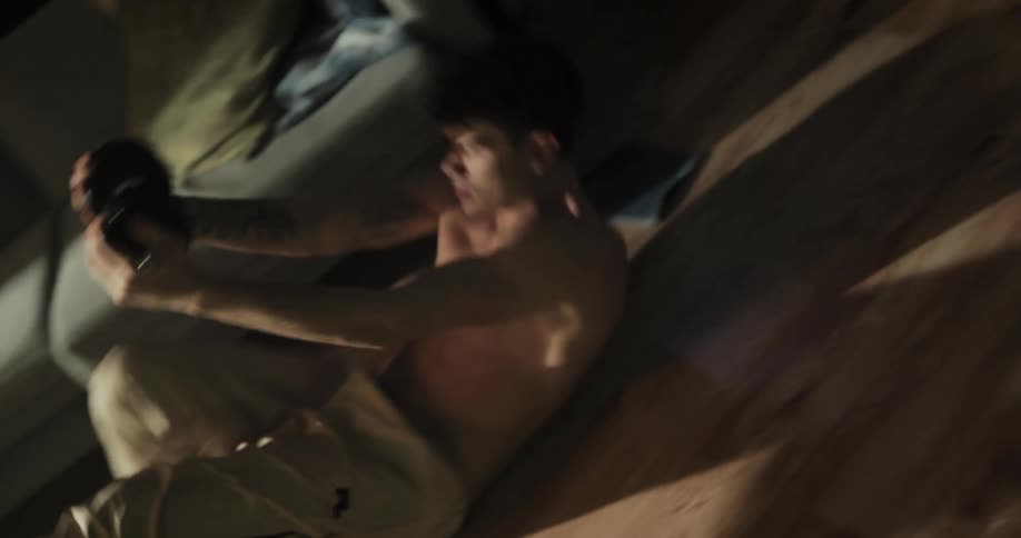A man exercises with a dumbbell in the living room of a house during the day