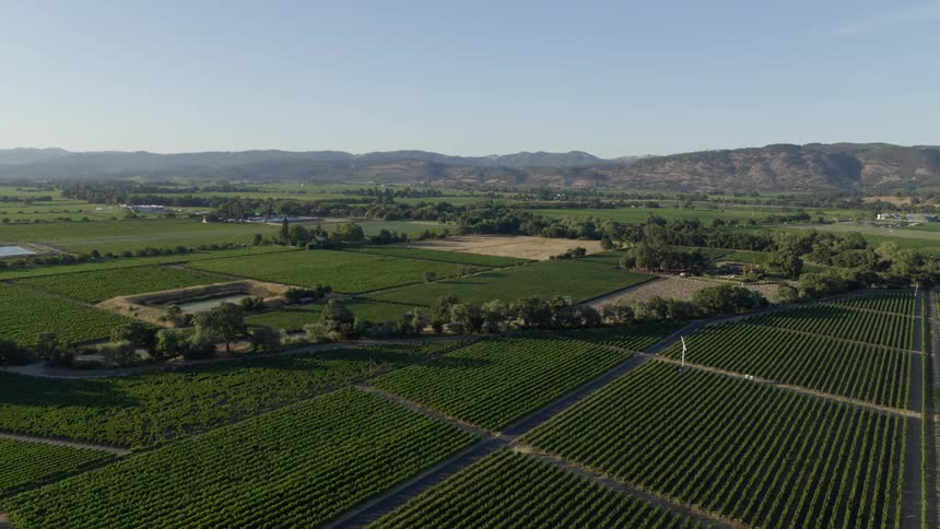 Soft morning light washes over picturesque farmland and countryside surrounded by mountains in the distance