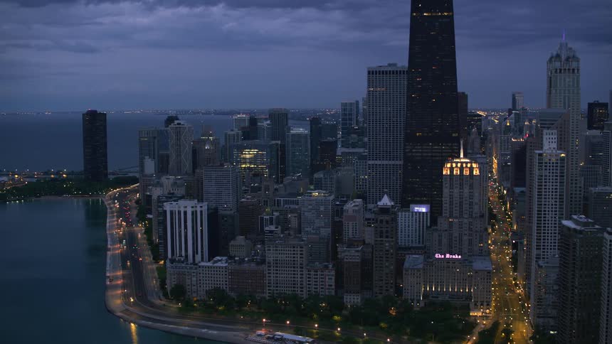 Tall buildings and skyscrapers along the coast of a metropolis on a cloudy night
