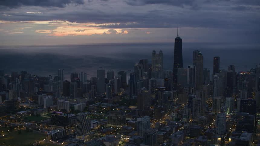 Thick clouds loom over the coastline of a metropolis at sunset