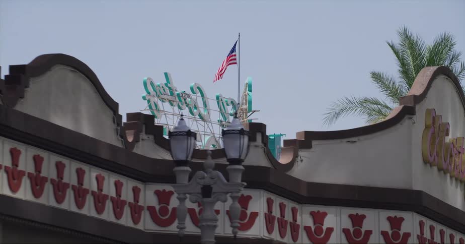 American flag flies over large sign near palm trees