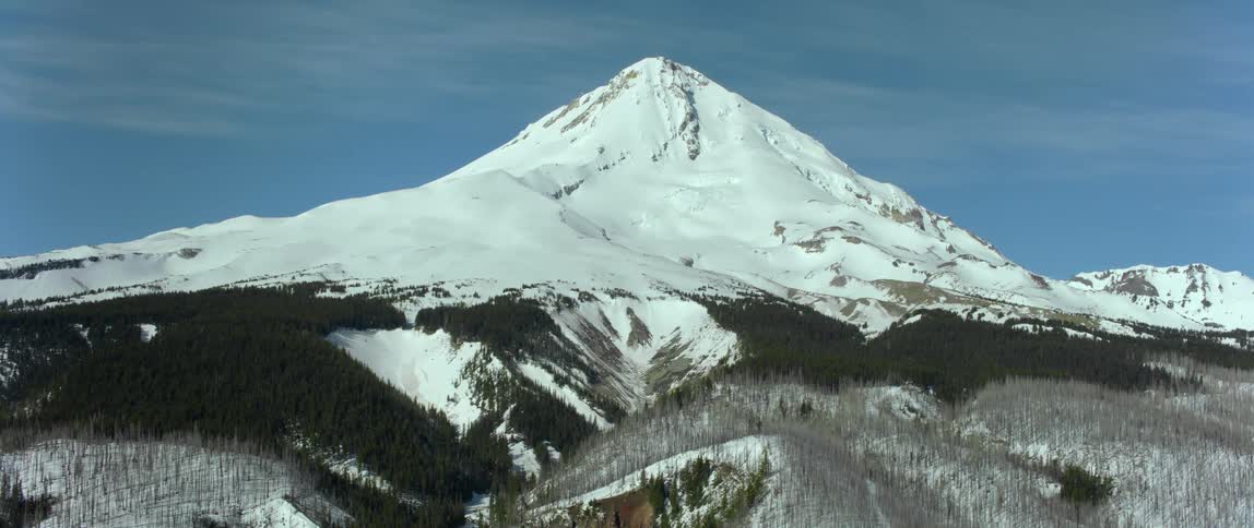 A snowy mountain peak under a clear blue daytime sky