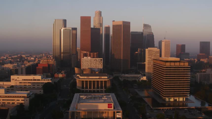 The sunlight shines on tall skyscrapers and towers as they stand high above other downtown buildings