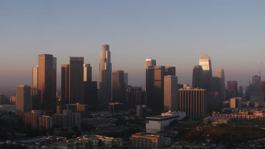 Skyscrapers standing against red tinted sky reflect suns glare
