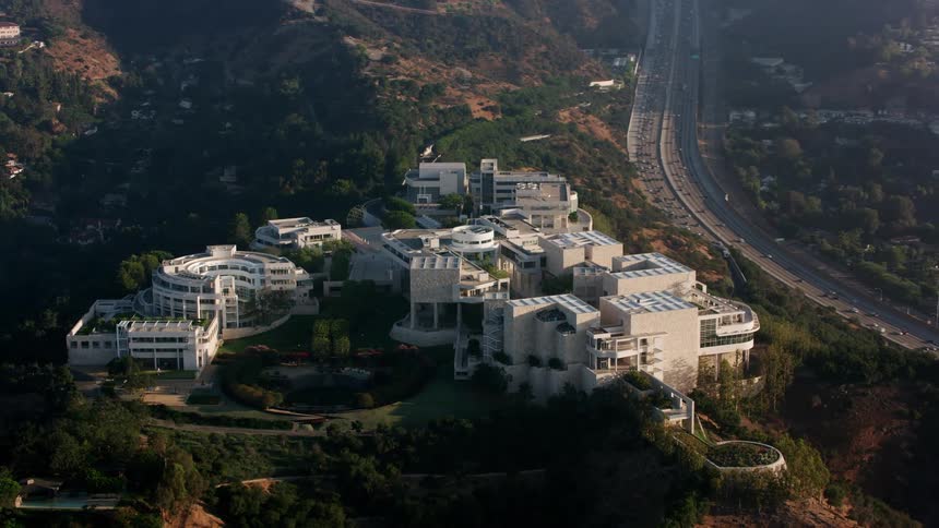 An aerial view of office buildings on a hill with vehicles driving on the street below