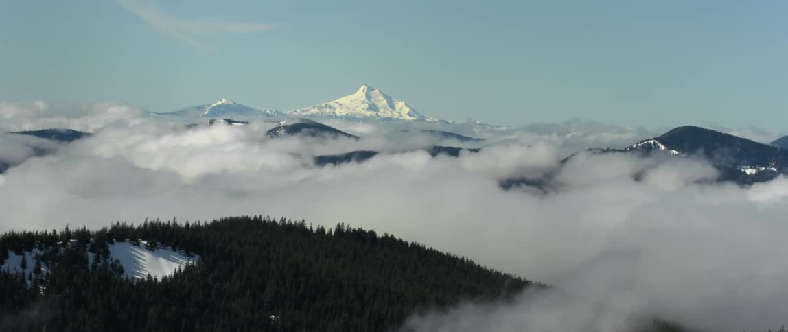 A snow covered mountain peak above the clouds