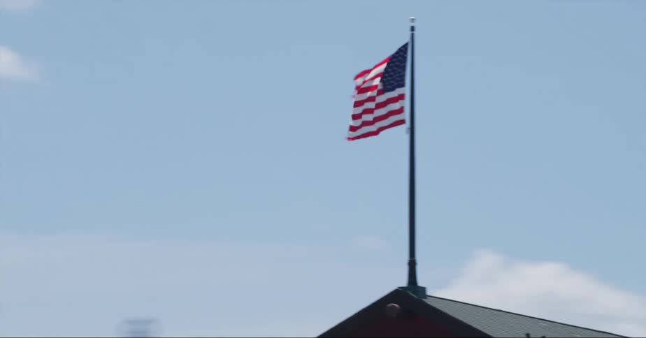 An american flag waves in the wind on a pole on top of a building