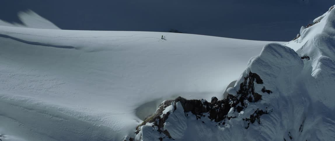 A skier on a mountain ridge standing alone on fresh powder