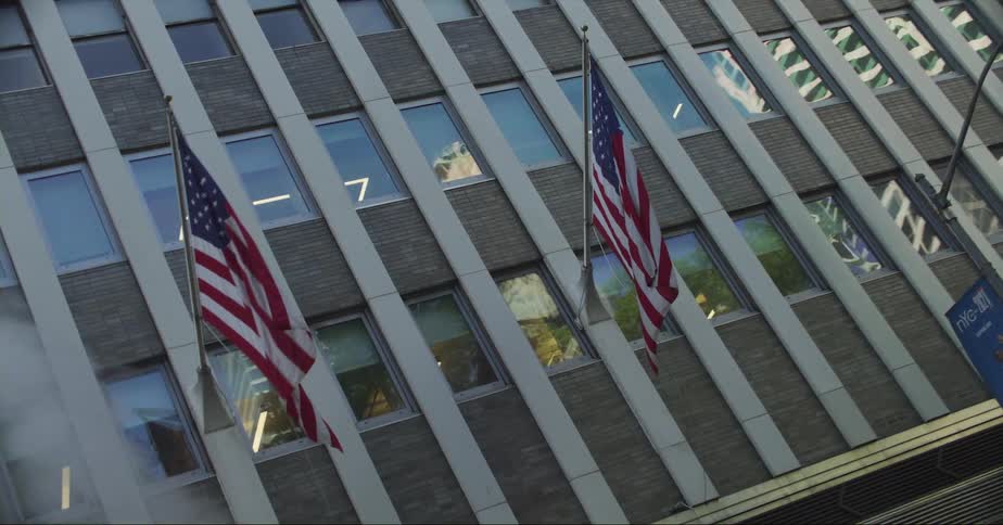 American flags fly on a building facade on a city street
