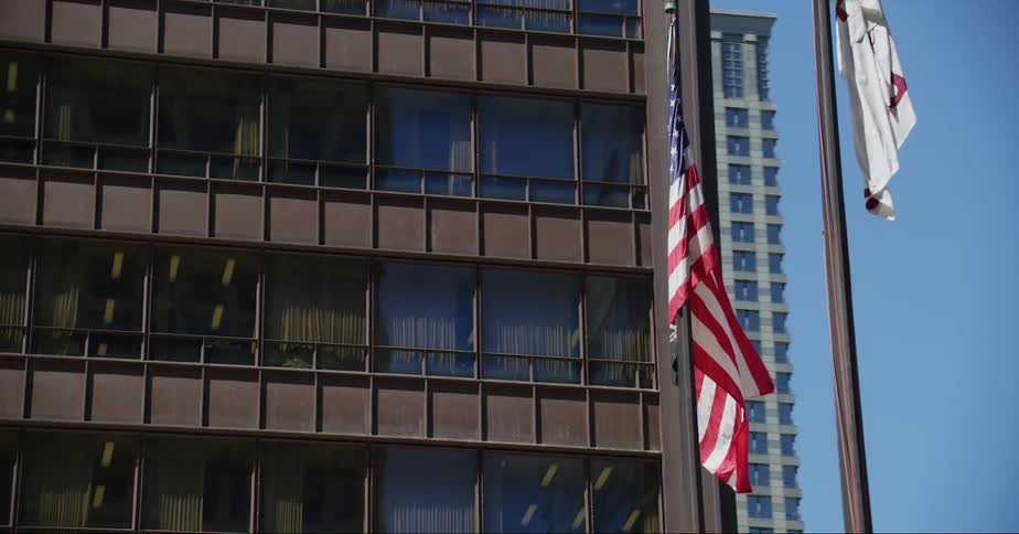 An american flag waves atop a pole in a metropolis during the day
