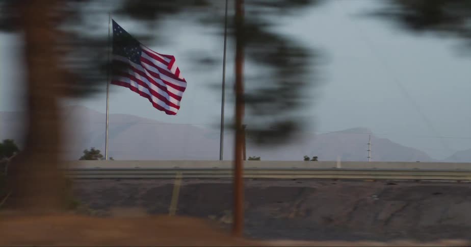 Trucks drive by on a highway near a mountain range