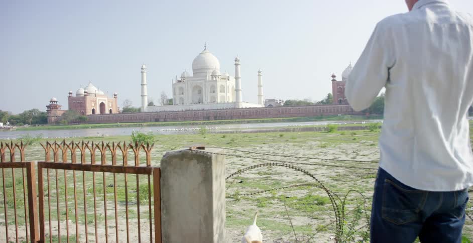 A man is photographing a large building in the distance