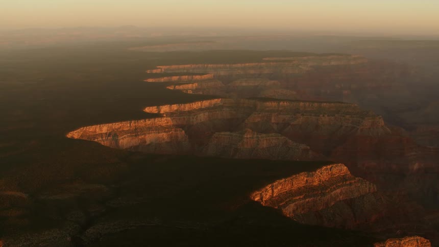 An immense canyon shrouded in fog at sunset