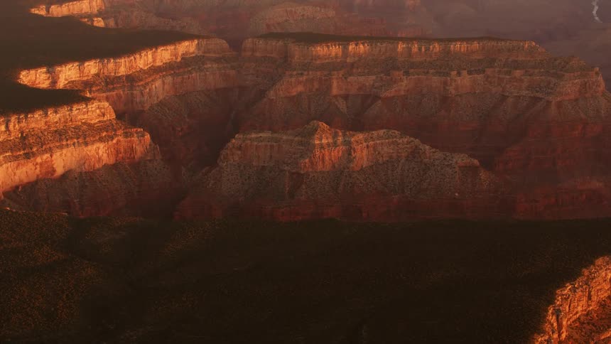 Red tinted cliff rock contrasts with dark shadowed plateaus