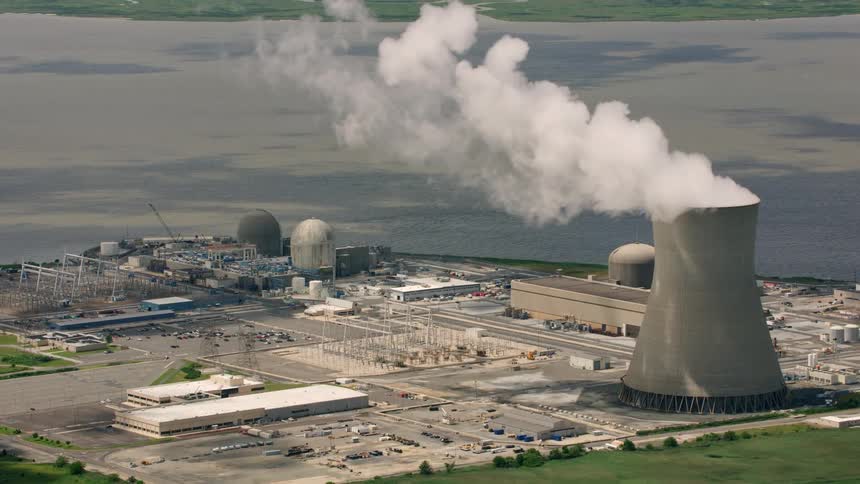 Heavy smoke rises from a smoke stack at a large factory